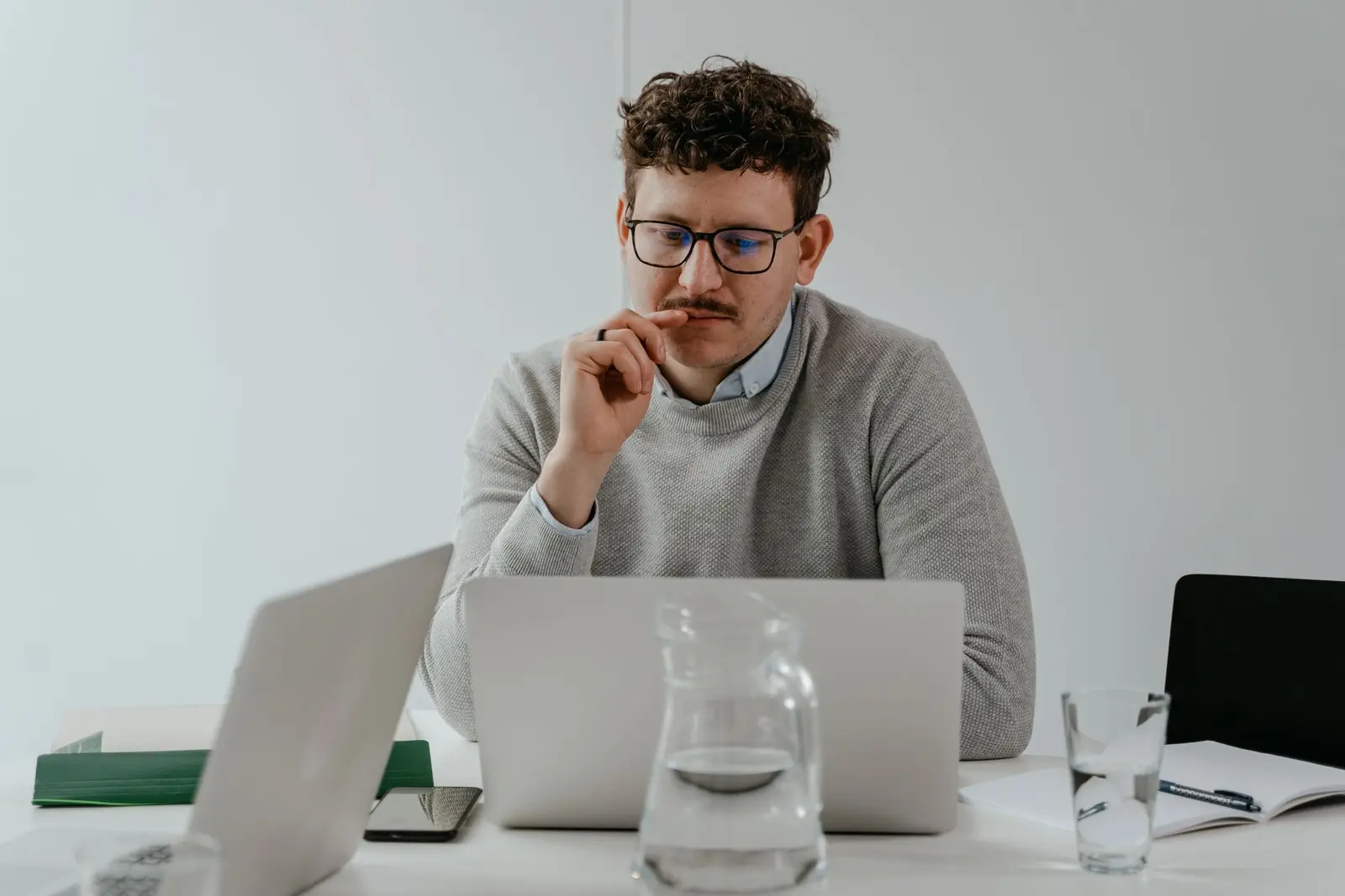 A man pausing at his laptop, working through a difficult decision