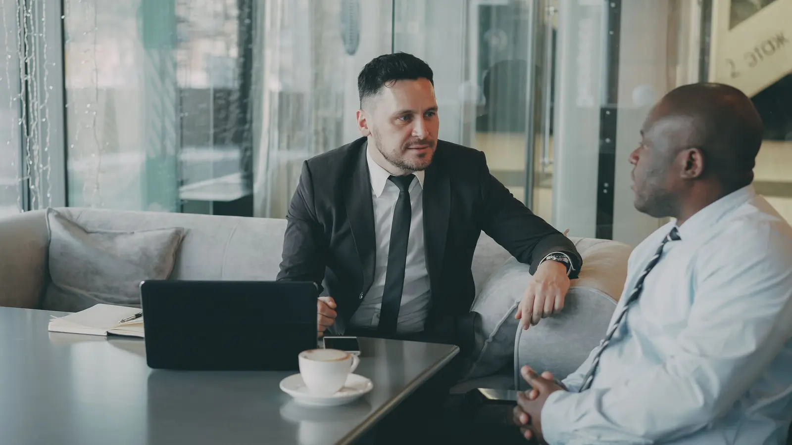 Two men talking through a plan over coffee in a business meeting