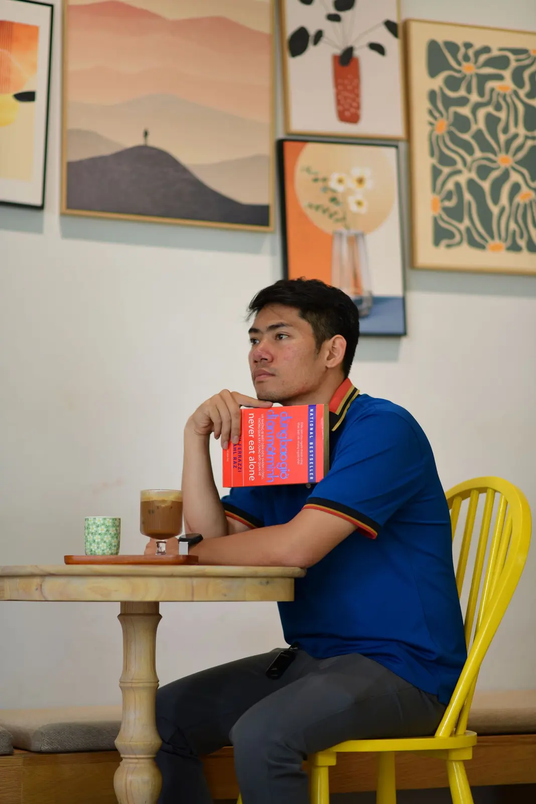 A man sitting with a book in a cafe, thinking through what he wants next