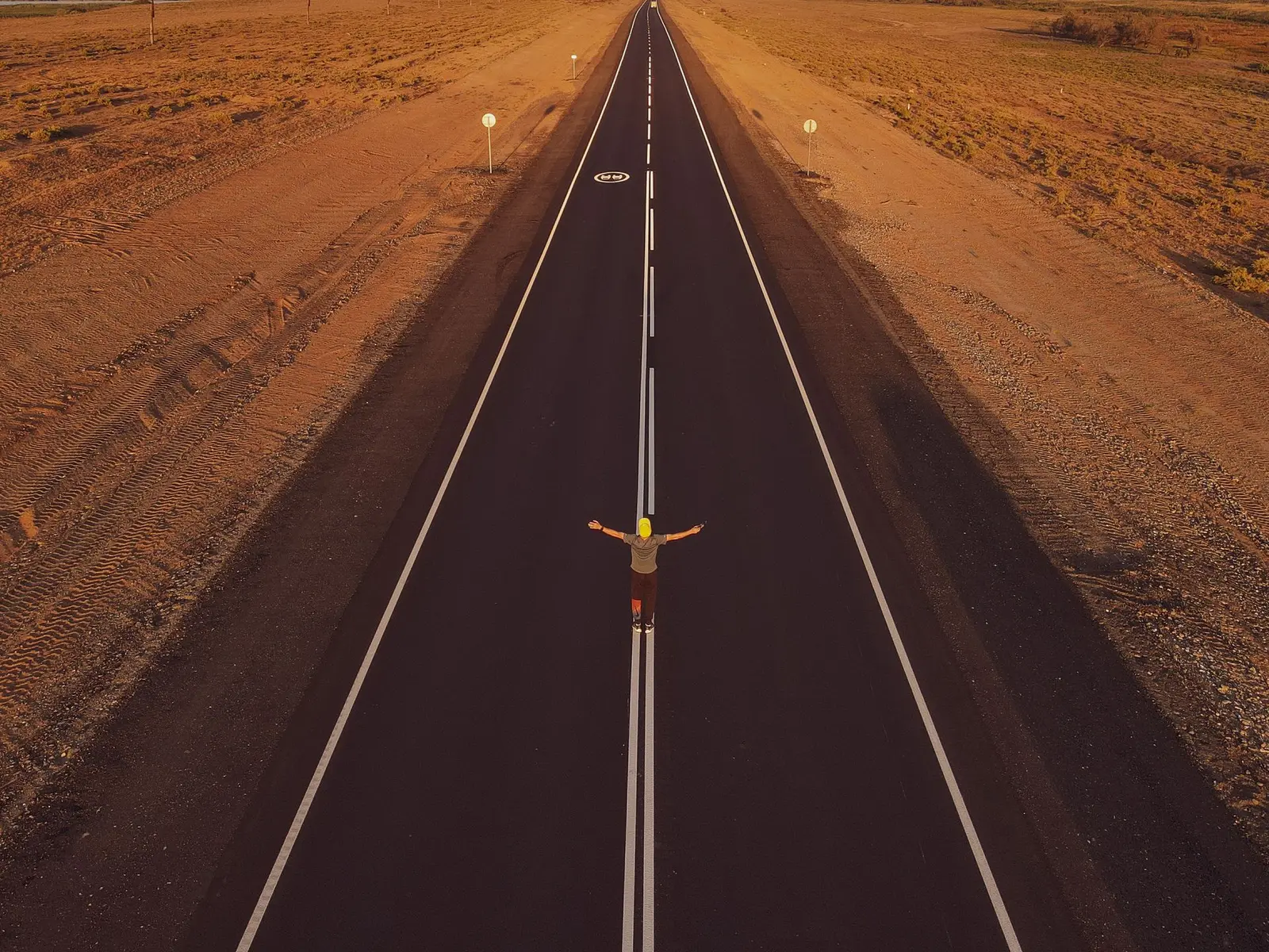 A man standing alone on an open road, arms out, ready for a fresh direction