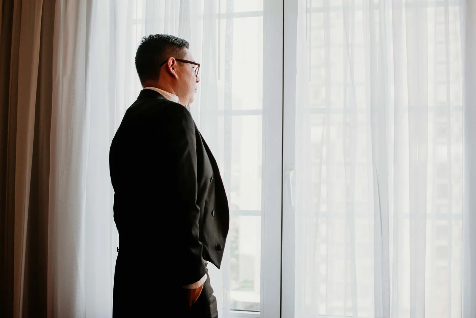 Man looking out a window, thinking through his next career move