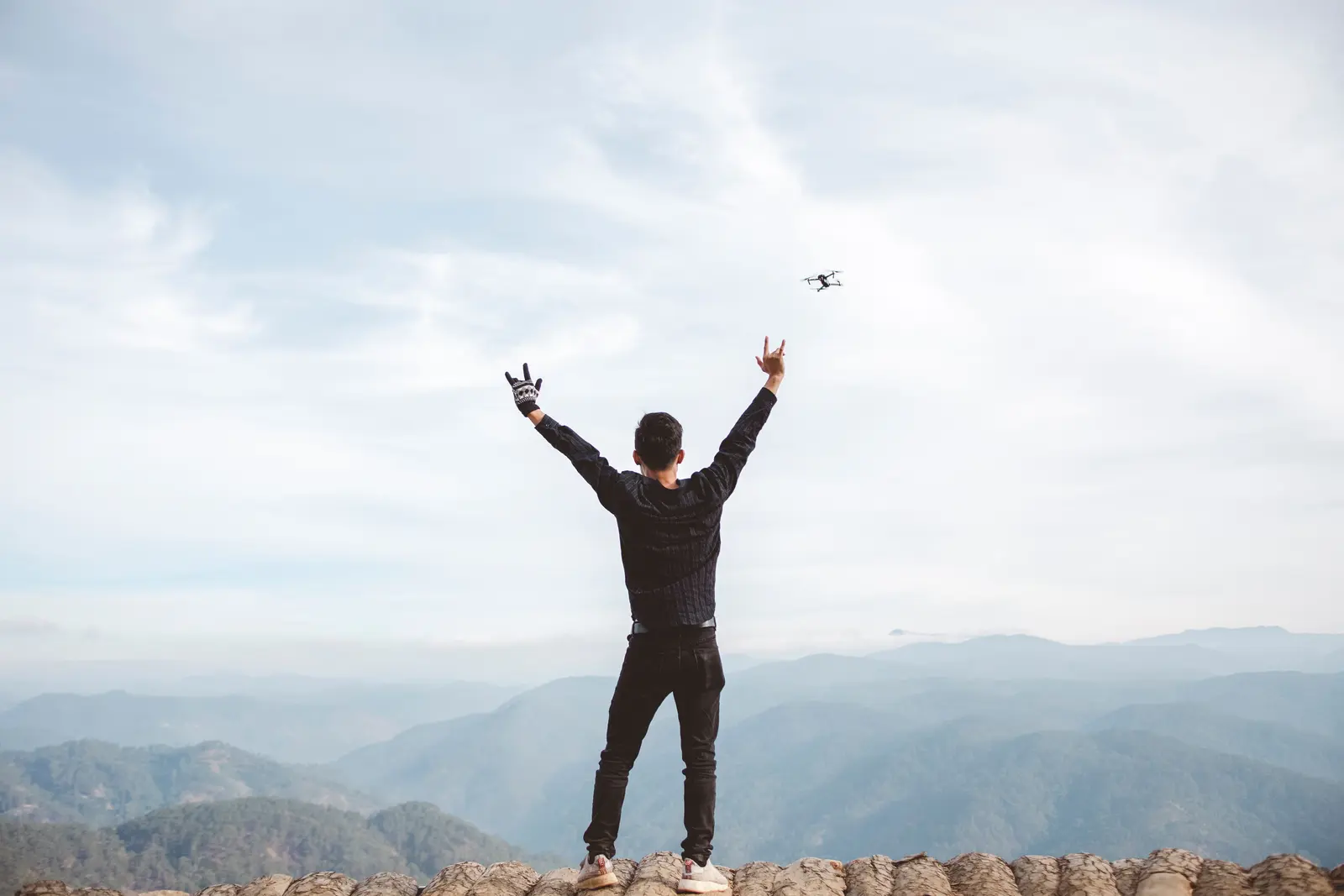 A man celebrating with arms raised on a mountaintop