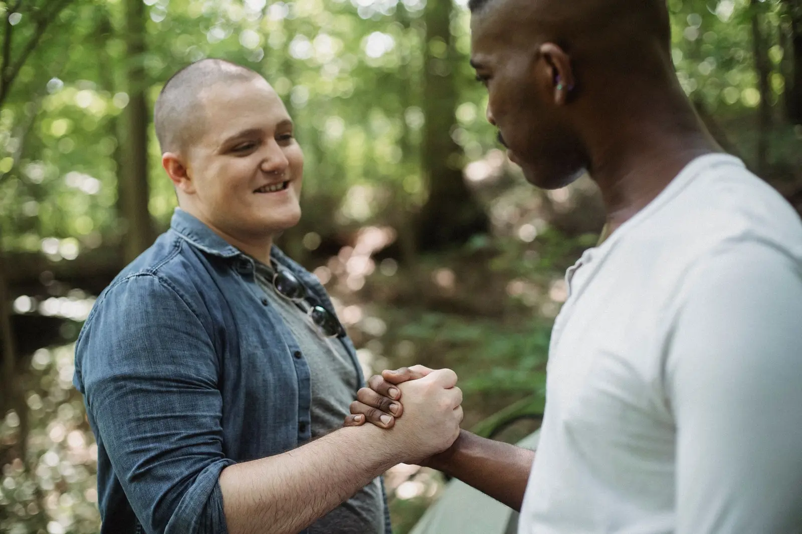 Two men shaking hands warmly outdoors, glad to reconnect