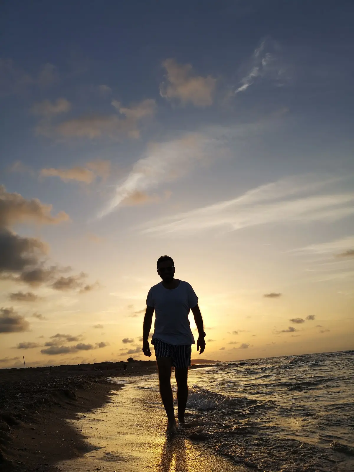 A man walking alone on the beach at sunset, working through his thoughts