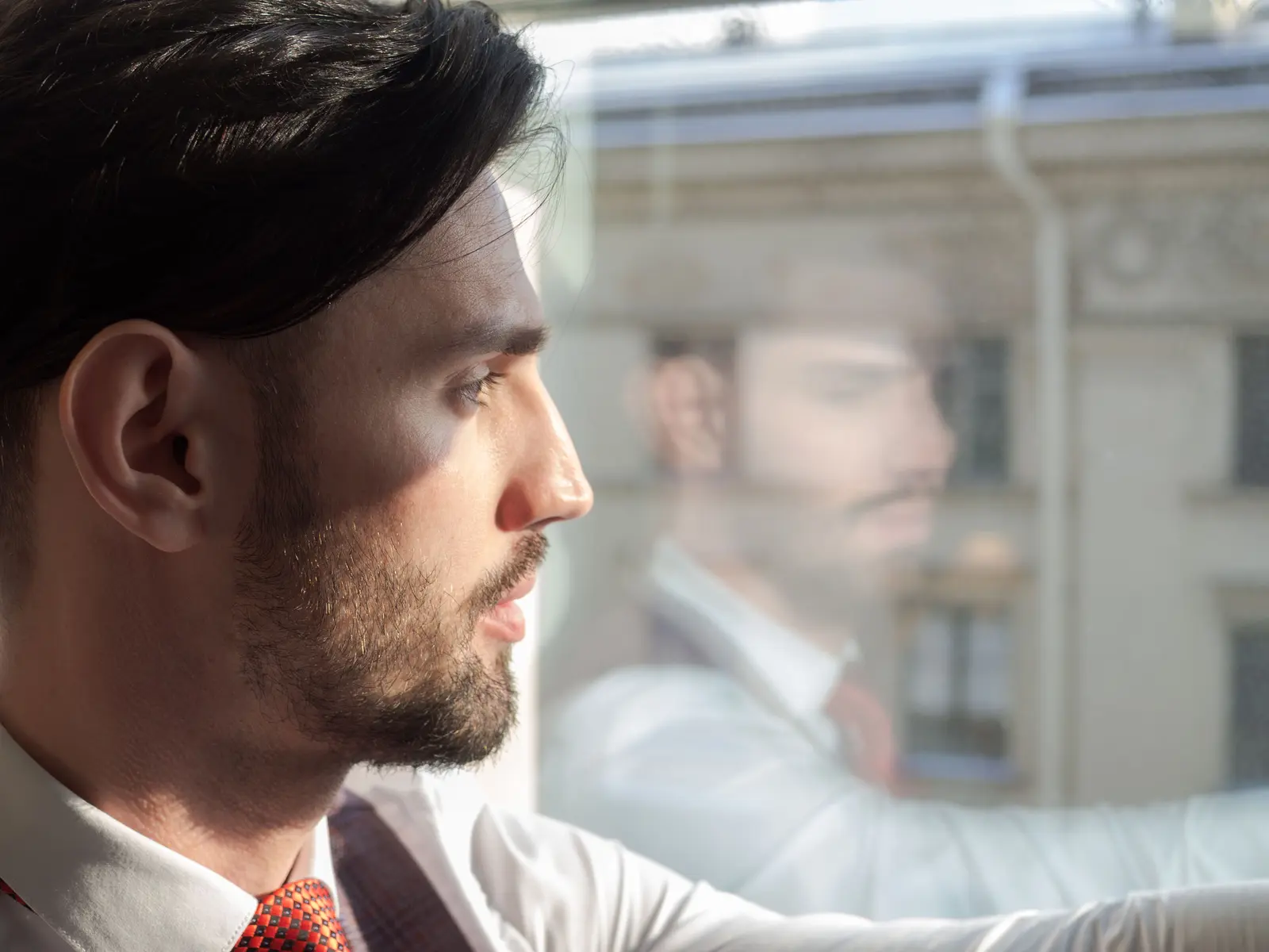 A man pausing to look out a window, lost in thought